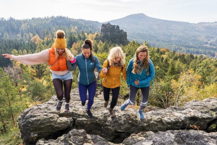 Four friends enjoying a joyful hike on Oybin's rocky terrain with scenic views.